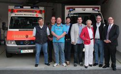 Foto: Alle neuen Vorstandsmitglieder vor dem Gerätewagen San, welcher in der Fahrzeughalle steht.